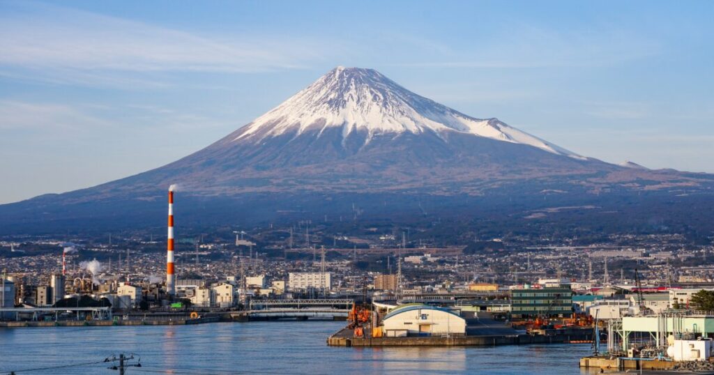 富士山と港の工業地帯が広がる海辺の風景