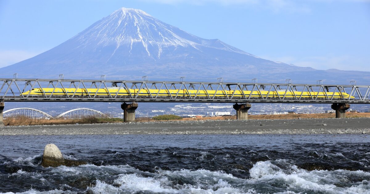 富士山と黄色い新幹線が鉄橋を走る風景
