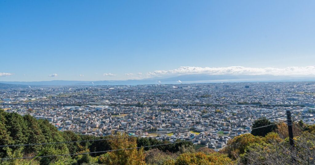 高台から見下ろす市街地と遠くの海のパノラマ風景