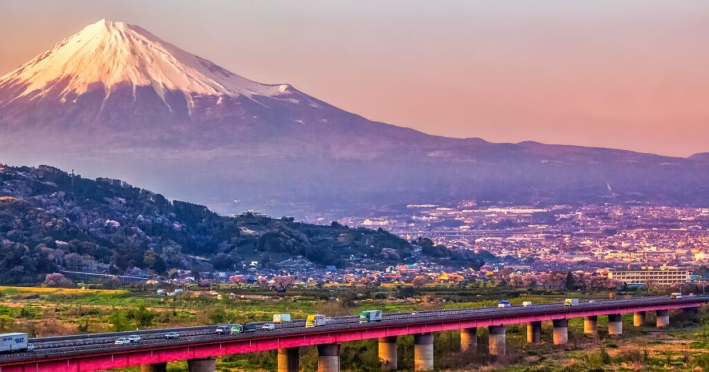 夕焼けに染まる富士山と橋を渡る車の風景