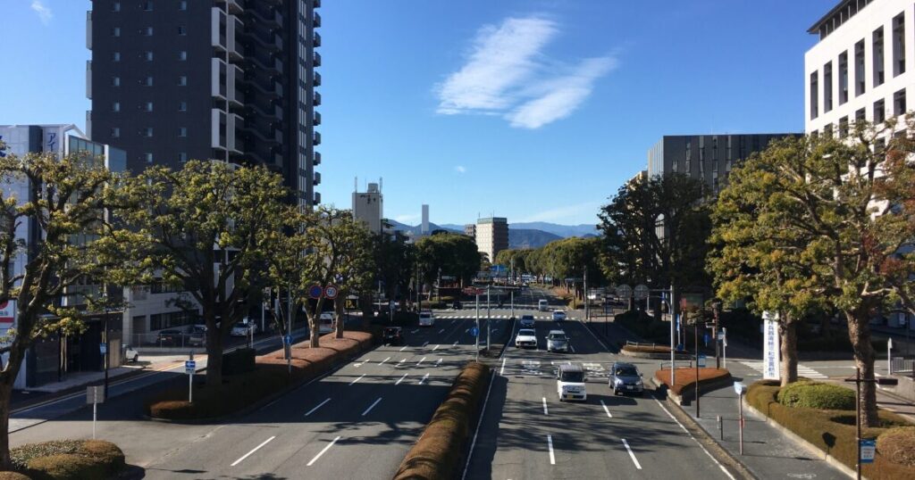 街路樹が並ぶ都市の大通りとビル群の風景