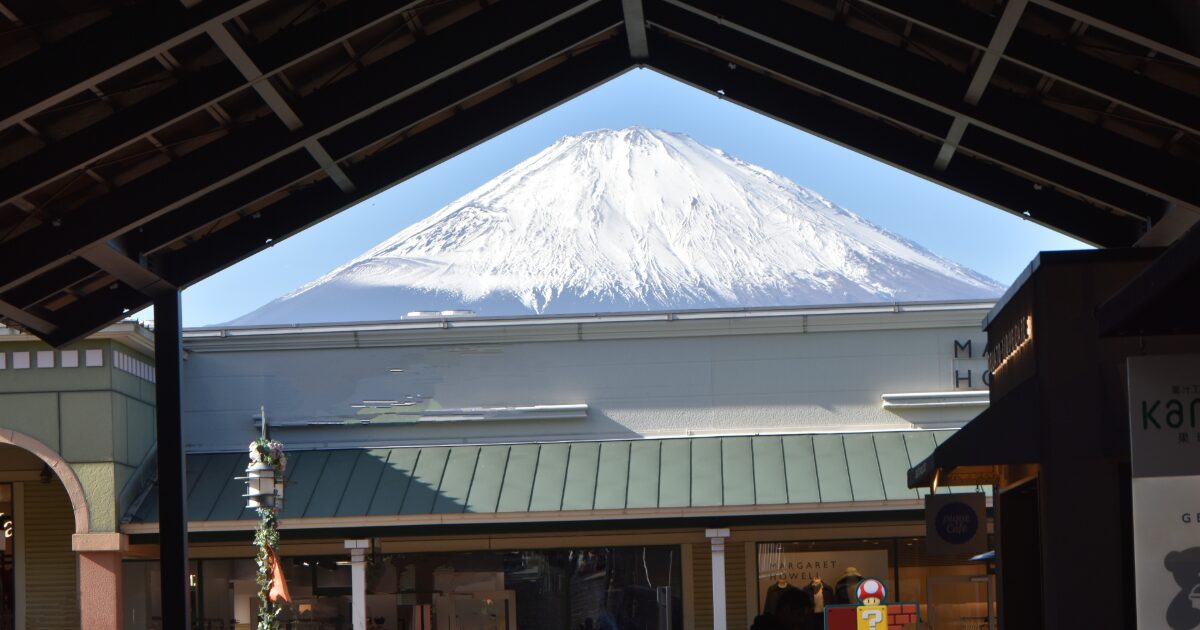 屋根のフレーム越しに見る富士山と商業施設