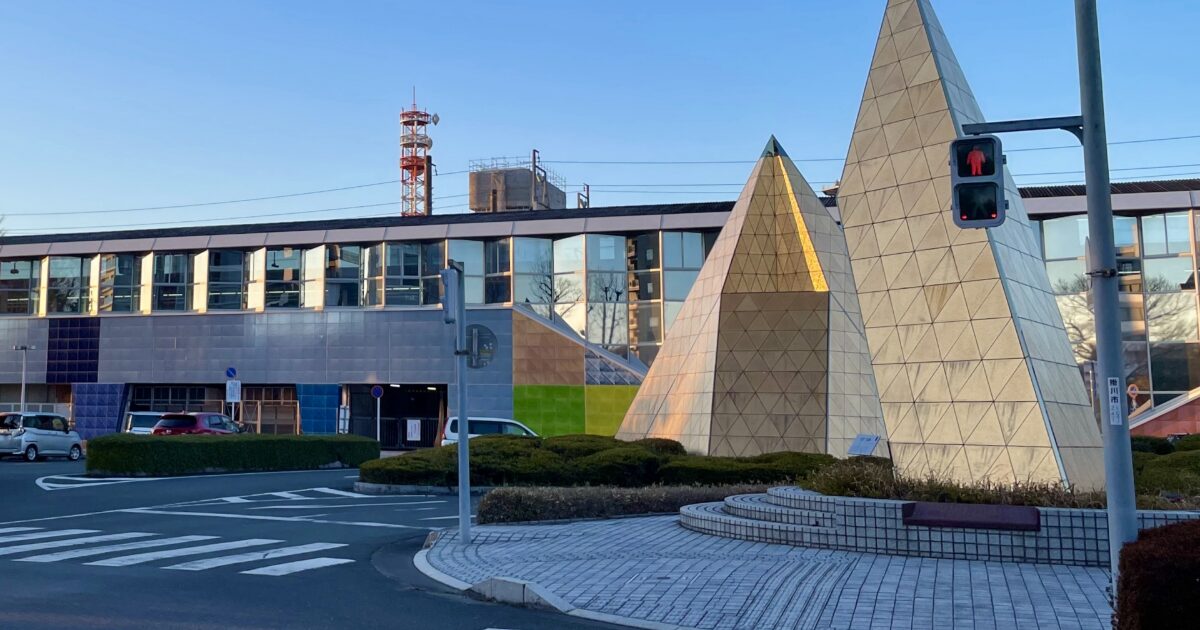 近代的な建物前に設置された三角形モニュメントと交差点