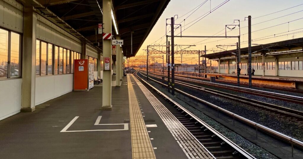 夕暮れの駅ホームと伸びる線路が続く鉄道風景