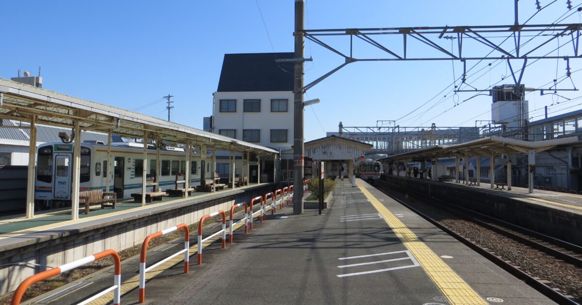 ローカル線のホームと停車中の列車がある駅構内の風景