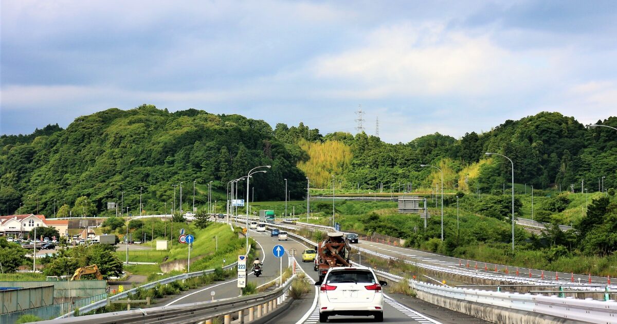 緑豊かな丘陵地帯を走る車と道路の風景