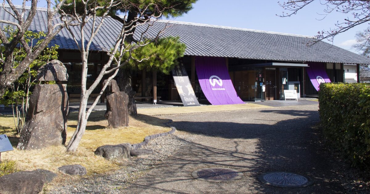 和風建築の施設入口と庭園に設置された石碑の風景