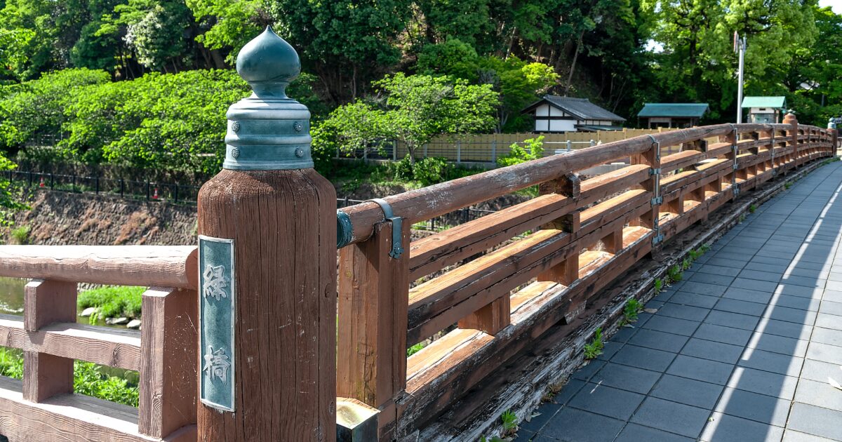 木製の橋と緑豊かな川沿いの遊歩道の風景