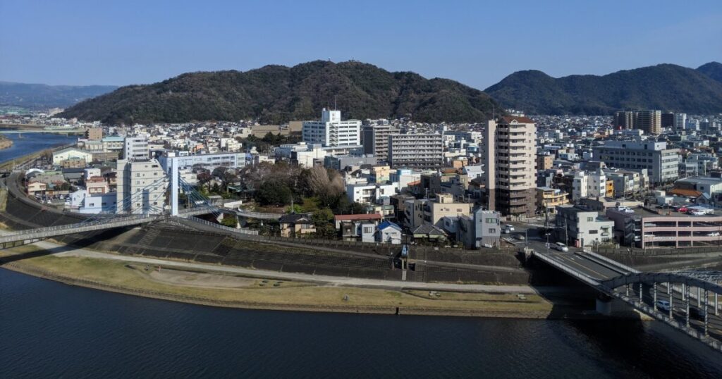 川沿いの市街地と橋が広がる山間の都市風景