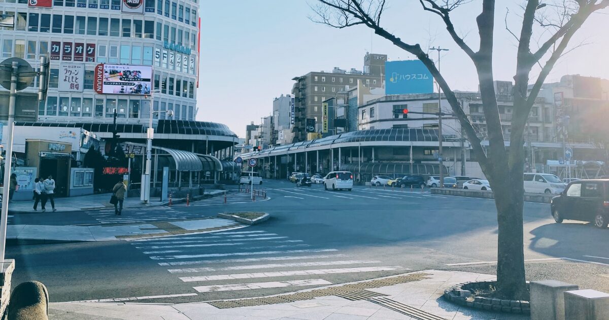 駅前交差点と商業ビルが並ぶ夕方の都市風景