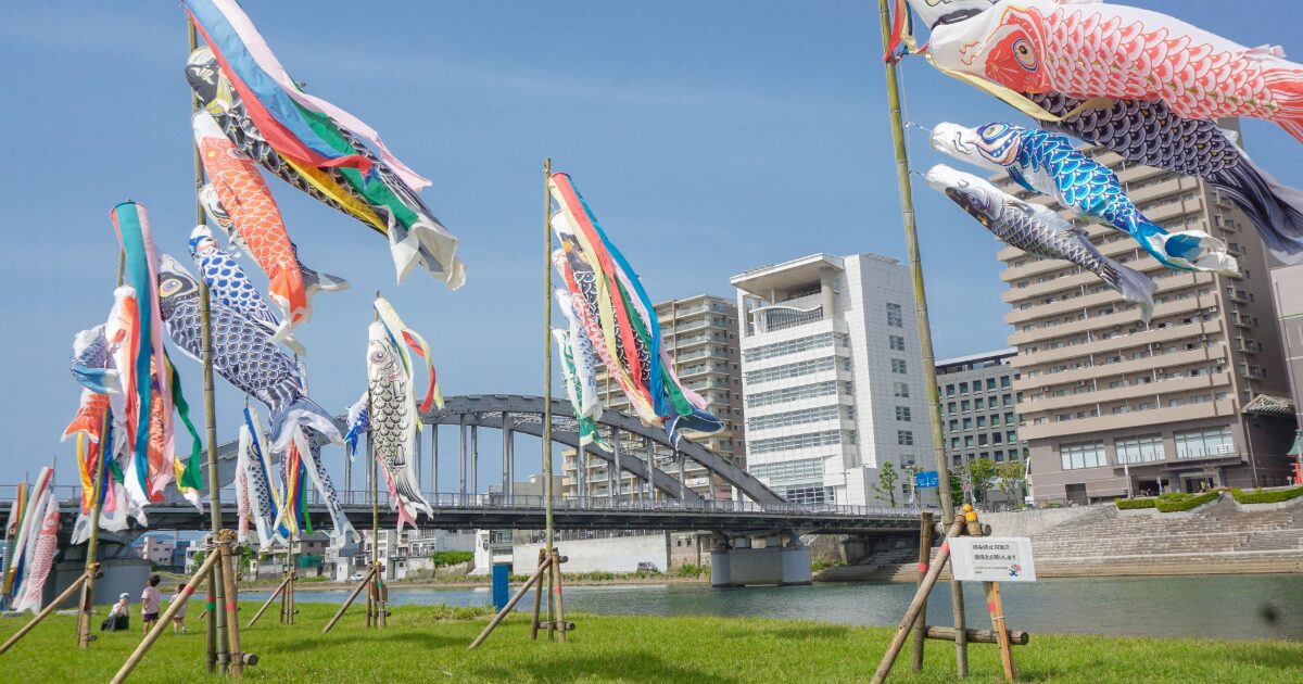 川沿いに並ぶ鯉のぼりと橋と都市の街並み