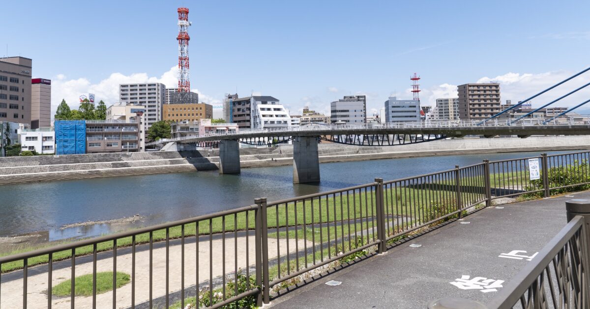 川に架かる橋と電波塔が見える市街地風景