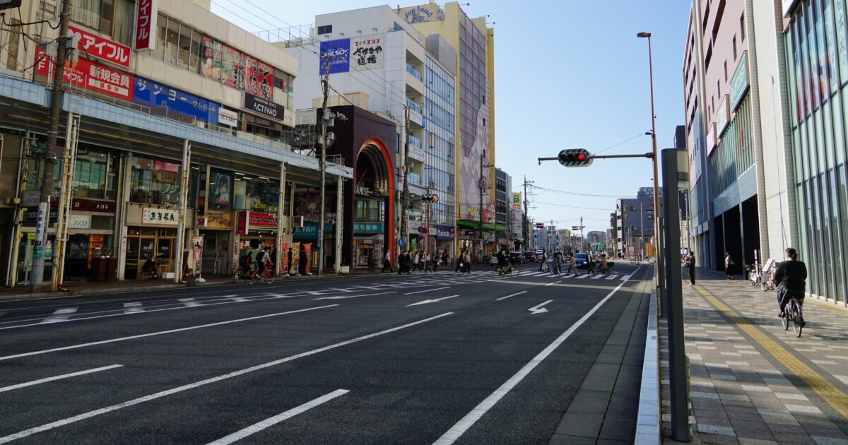 商店街入口と広い道路に人が行き交う街並み
