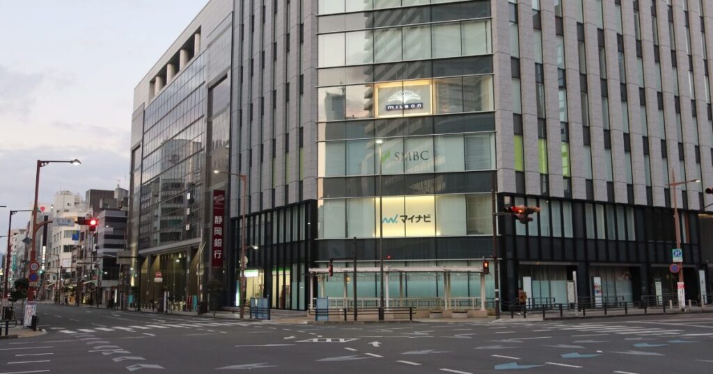 都市の交差点に立つガラス張りの大型オフィスビル外観