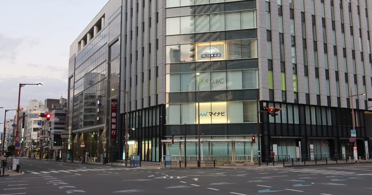 都市の交差点に立つガラス張りの大型オフィスビル外観