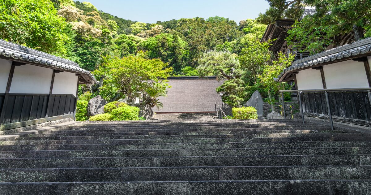 石段を上ると現れる日本庭園と伝統的な建物の景観