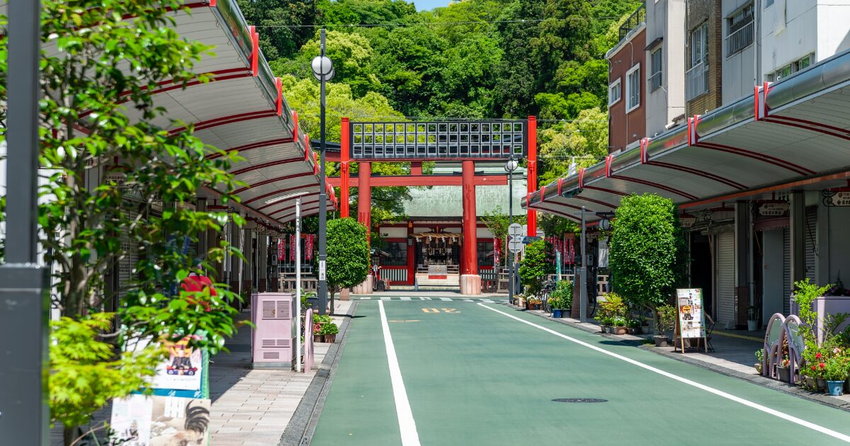 赤い鳥居が見える商店街の通りと神社参道の風景