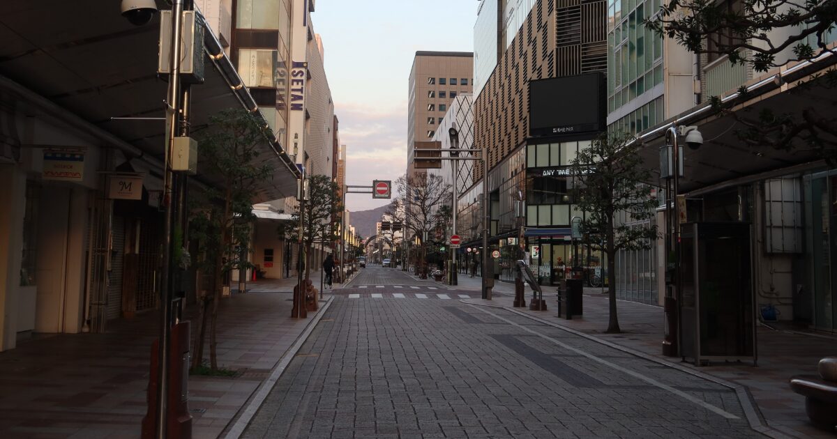 石畳の歩道が続く静かな商店街の朝の風景