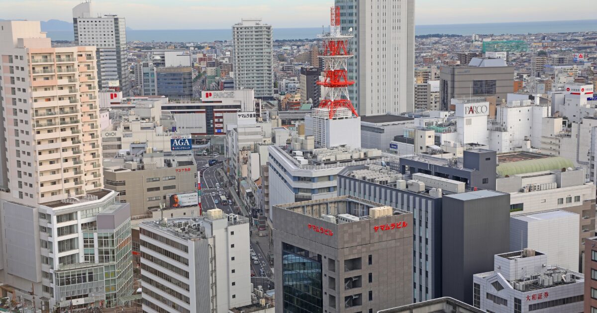 赤白の電波塔と高層ビル群が広がる都市の景観