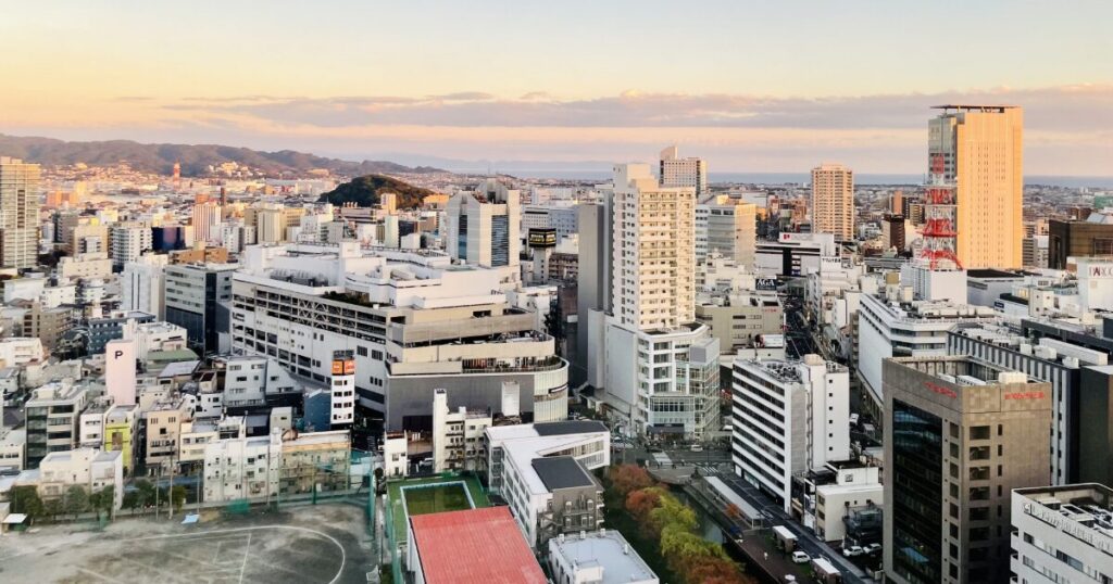 夕焼けに染まる高層ビル群と電波塔が見える都市全景