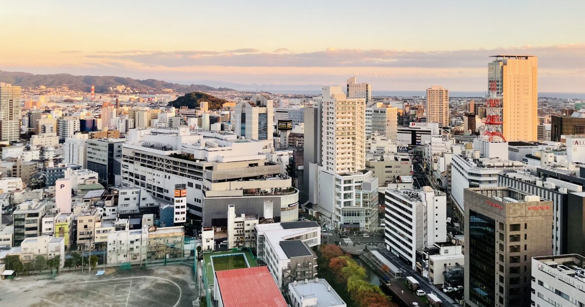 夕焼けに染まる高層ビル群と電波塔が見える都市全景