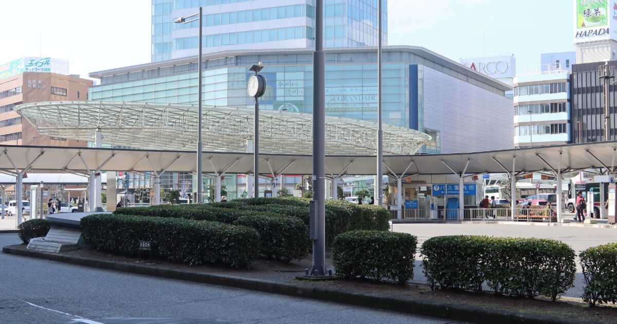 駅前ロータリーとガラス張り商業施設が広がる都市風景