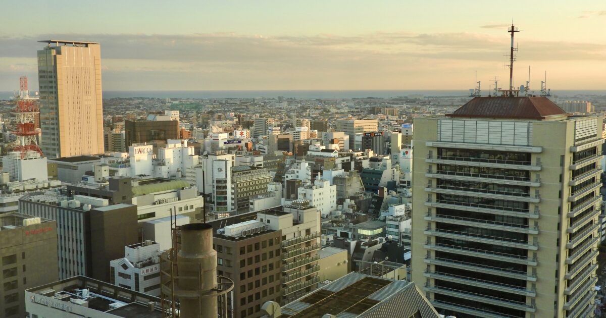 夕暮れの都市を一望できる高層ビル群と遠くの海の景色